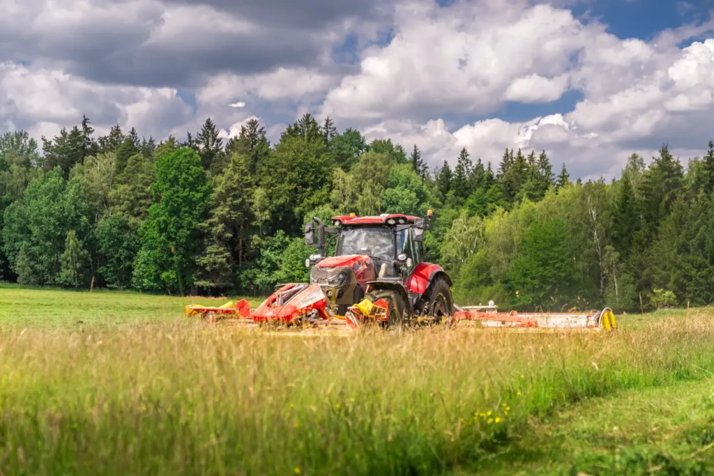 Traktor s žacím strojem na louce