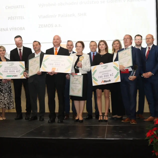 Skupinová fotografie vítězů a organizátorů soutěže Zemědělec roku 2024, držící ocenění a symbolické šeky na 100 000 Kč.